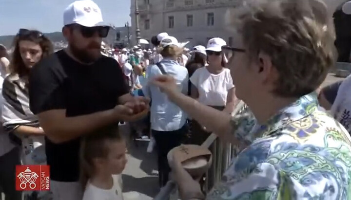 A woman administering Catholic communion to the willing. Photo: Vatican News YouTube Channel